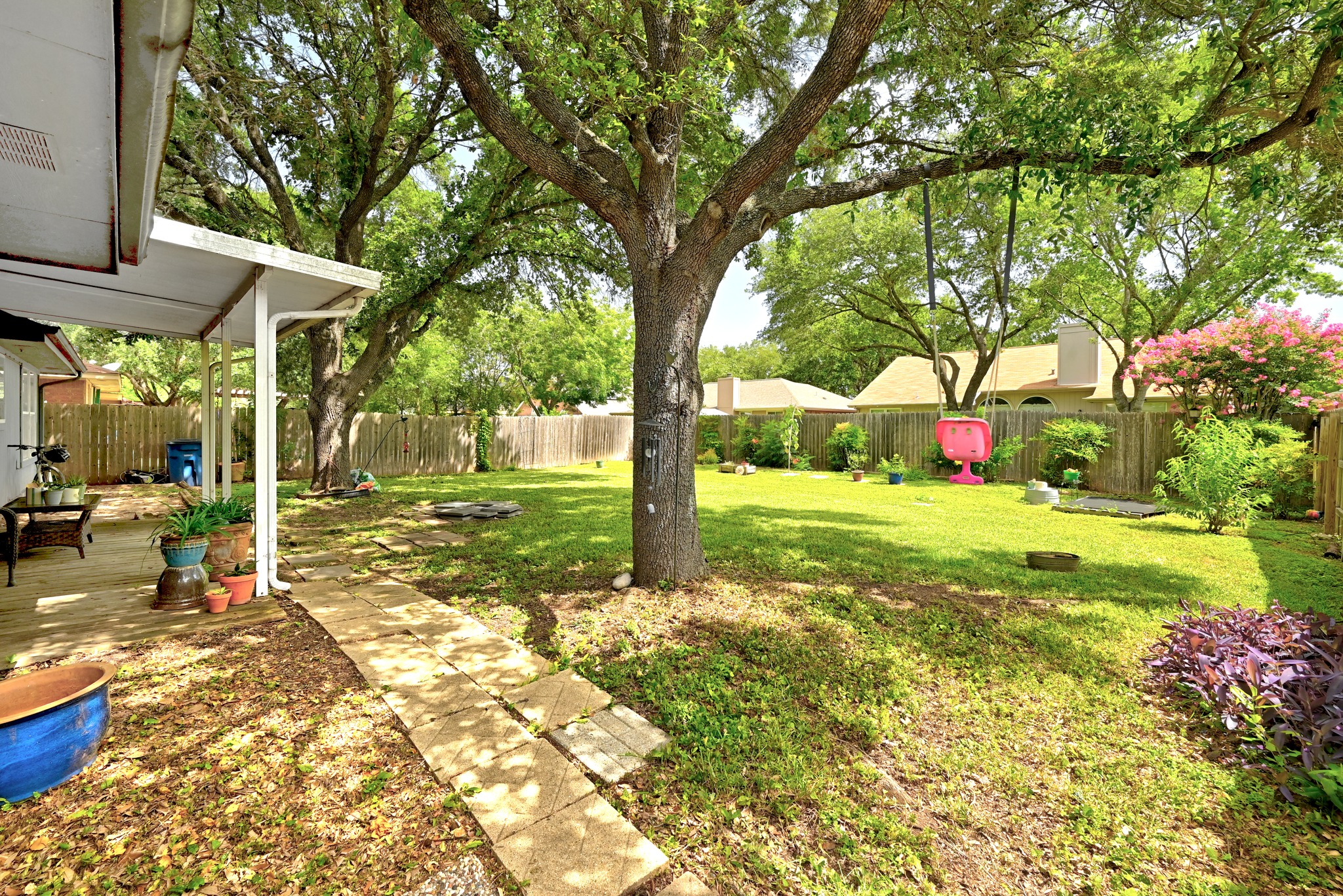 6412 Colton-Bluff Springs Road Austin, TX 78744 - Photo 22 of 27 A spacious backyard with mature trees, a wooden fence, and a patio area, perfect for outdoor relaxation.