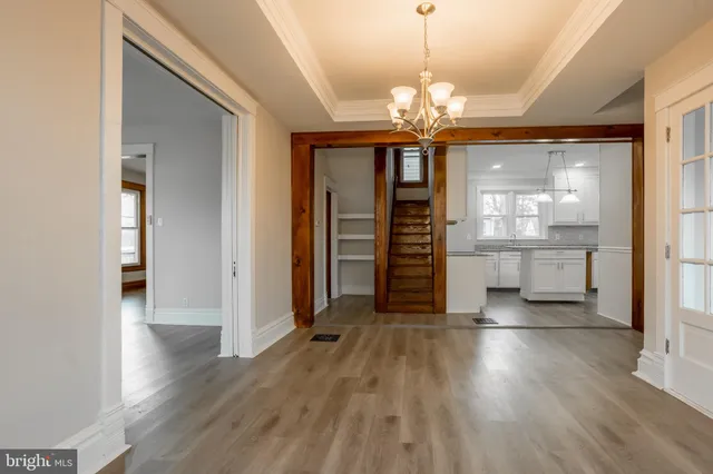 an empty room with wooden floor chandelier and windows