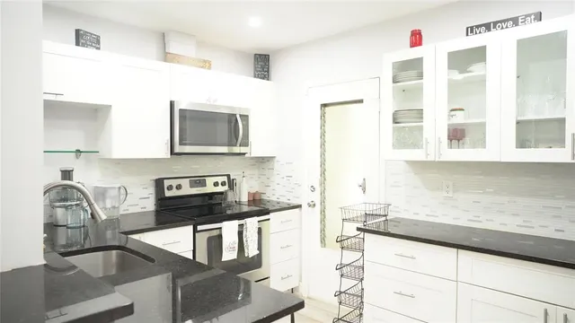 a kitchen with granite countertop a stove a sink and a microwave