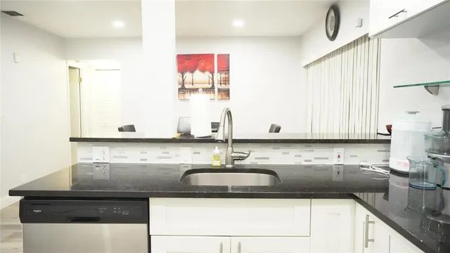 a kitchen with stainless steel appliances granite countertop a sink and a white cabinets