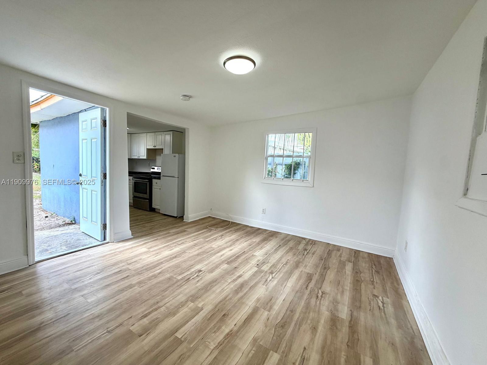 1060 Northwest 116th Street, Unit 3 Miami, FL 33168 - Photo 5 of 9 a view of empty room with kitchen and wooden floor