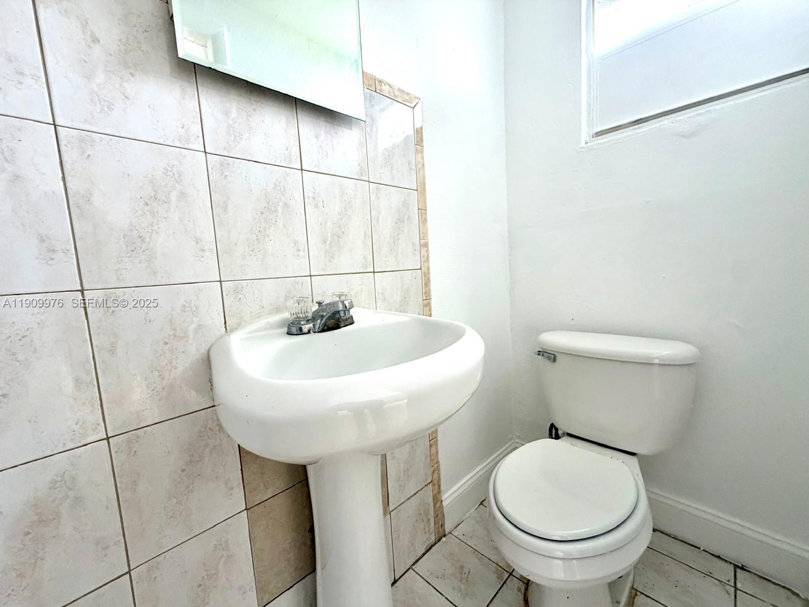 1060 Northwest 116th Street, Unit 3 Miami, FL 33168 - Photo 7 of 9 a bathroom with a sink a toilet and a mirror