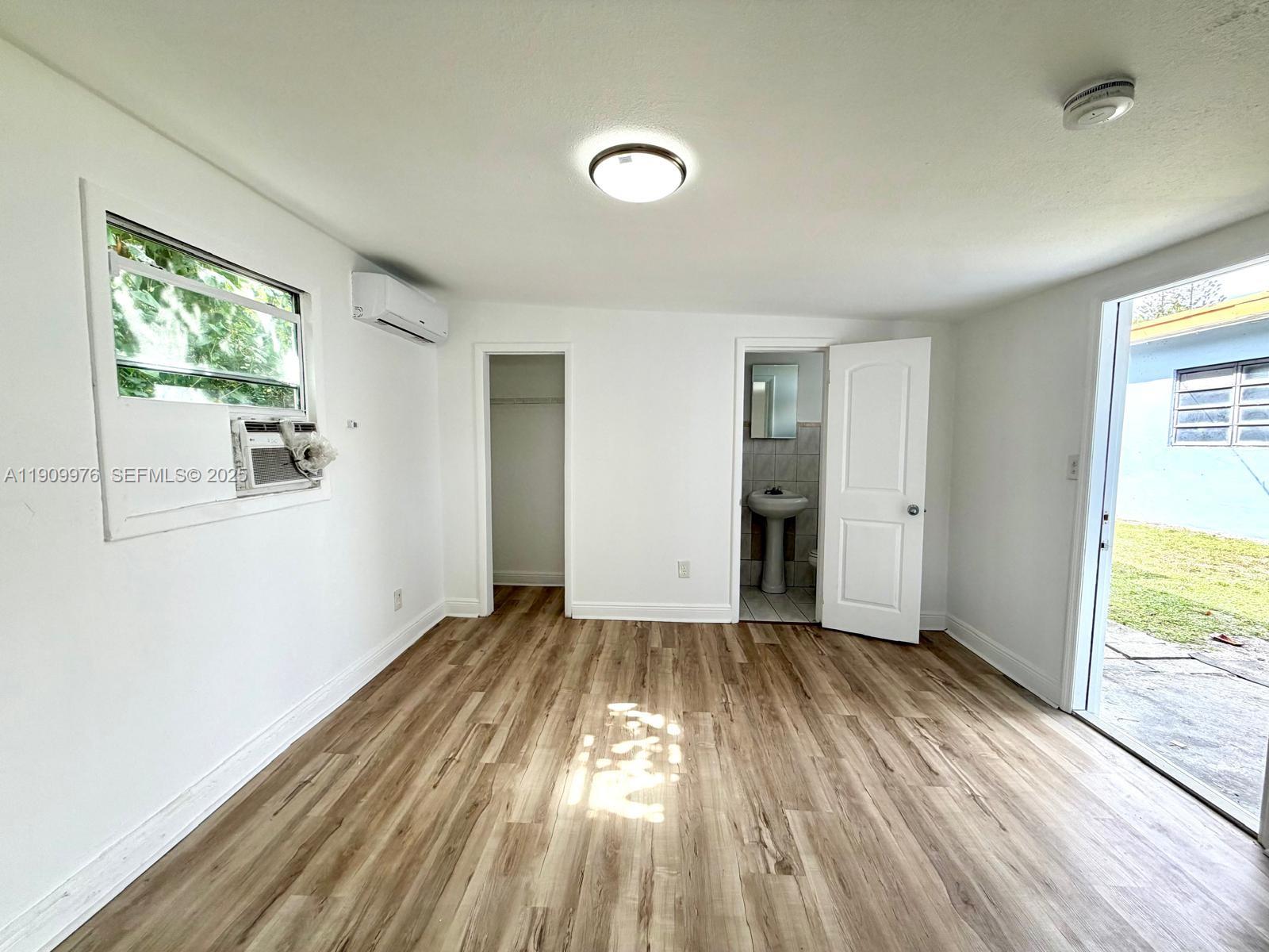 1060 Northwest 116th Street, Unit 3 Miami, FL 33168 - Photo 8 of 9 an empty room with wooden floor and windows