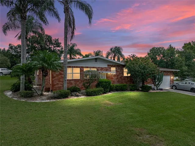 a front view of a house with garden and trees