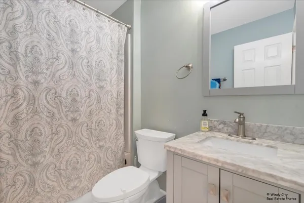 a bathroom with a granite countertop sink and a toilet