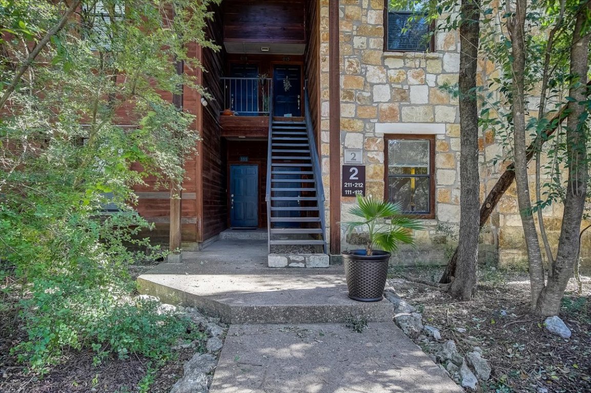 a view of a house with a potted plant and a large tree
