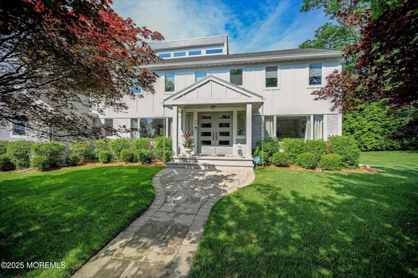 a view of a white house next to a yard with big trees
