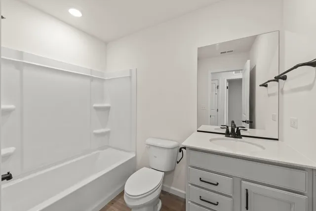 a bathroom with a granite countertop sink a toilet a mirror and shower