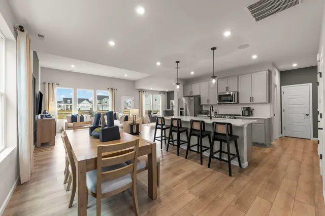 a view of a dining room with furniture wooden floor and a kitchen view