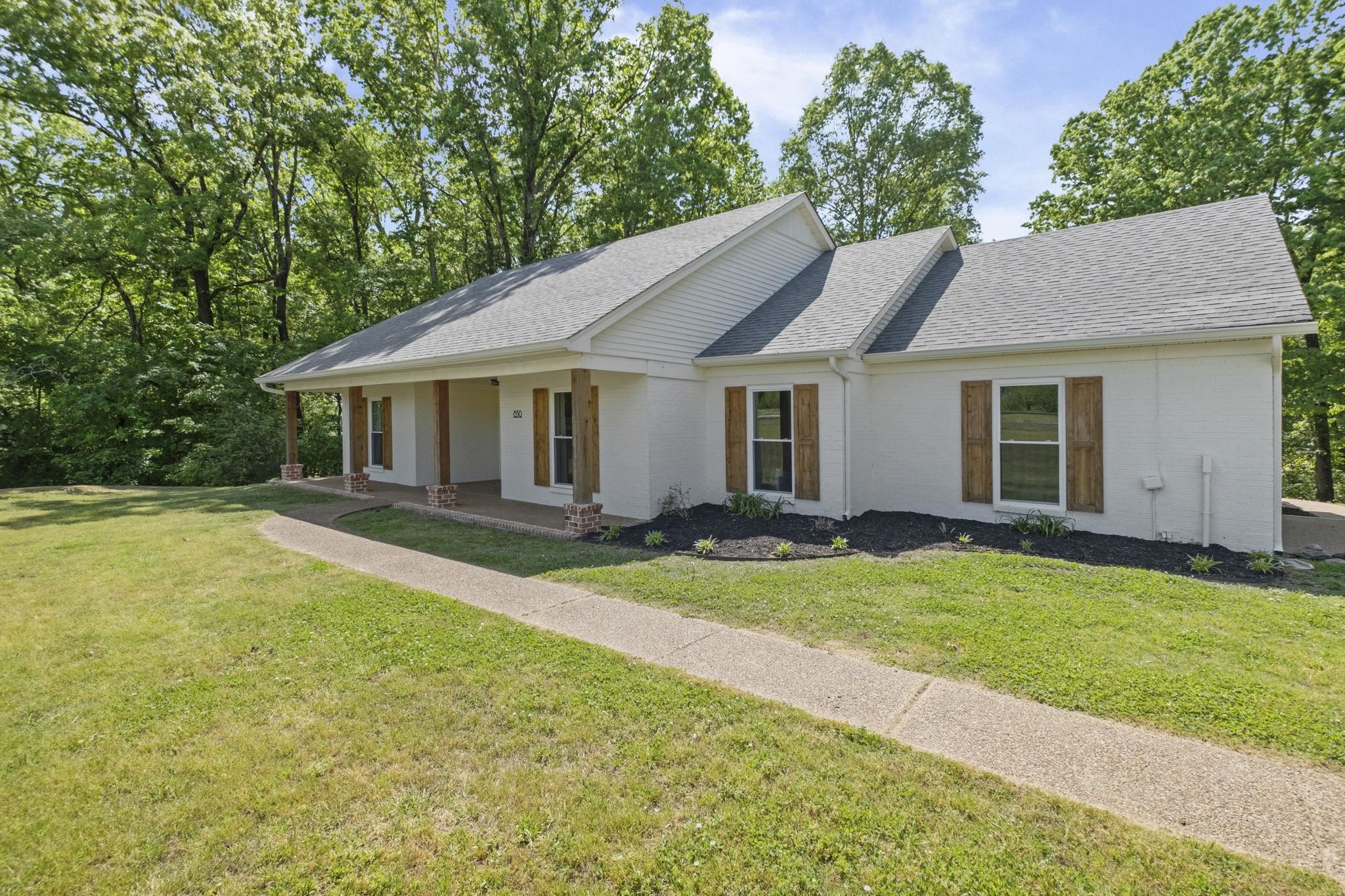 650 Firetower Road Somerville, TN 38068 - Photo 1 of 39 Ranch-style home with a shingled roof, a porch, a front lawn, and brick siding