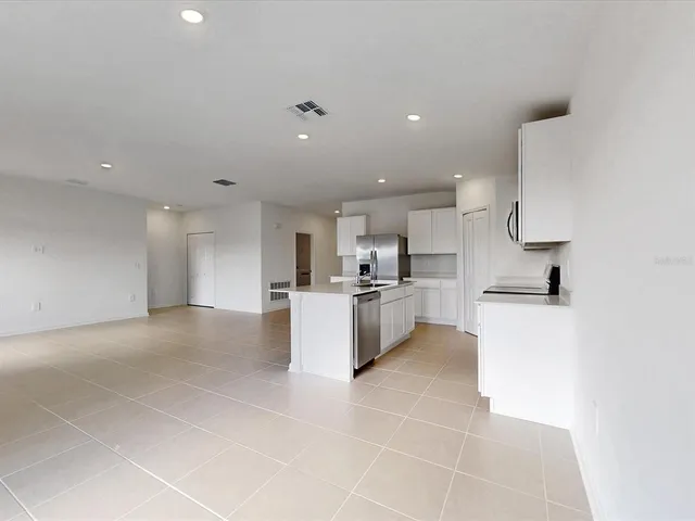 a large white kitchen with kitchen island a sink a counter and a stove top oven