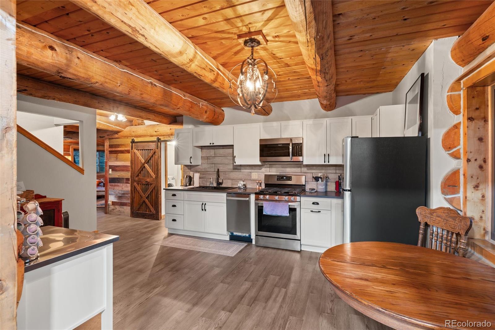 1853 County Road Kremmling, CO 80459 - Photo 33 of 50 a kitchen with stainless steel appliances granite countertop a refrigerator a stove top oven a sink dishwasher and white cabinets with wooden floor