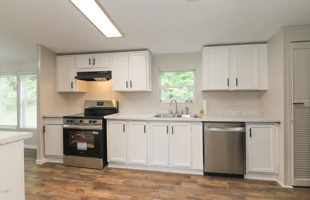 a kitchen with granite countertop a stove sink and cabinets