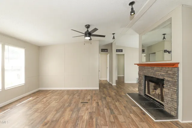 an empty room with windows fireplace and wooden floor