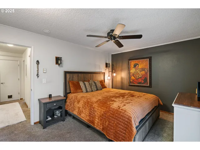 a bedroom with a bed a dresser and potted plant