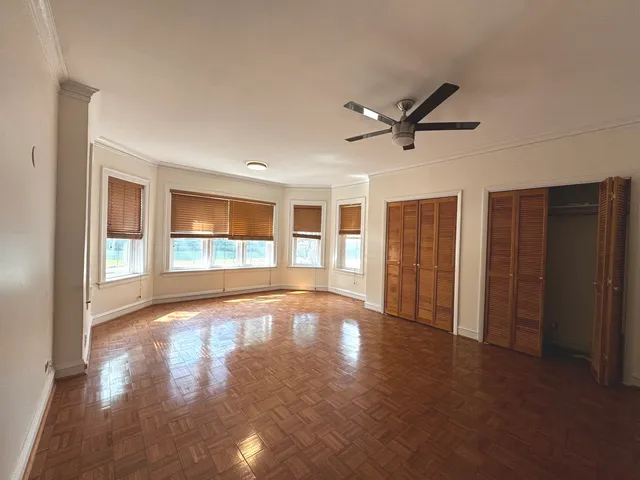 a view of an empty room with a window and wooden floor
