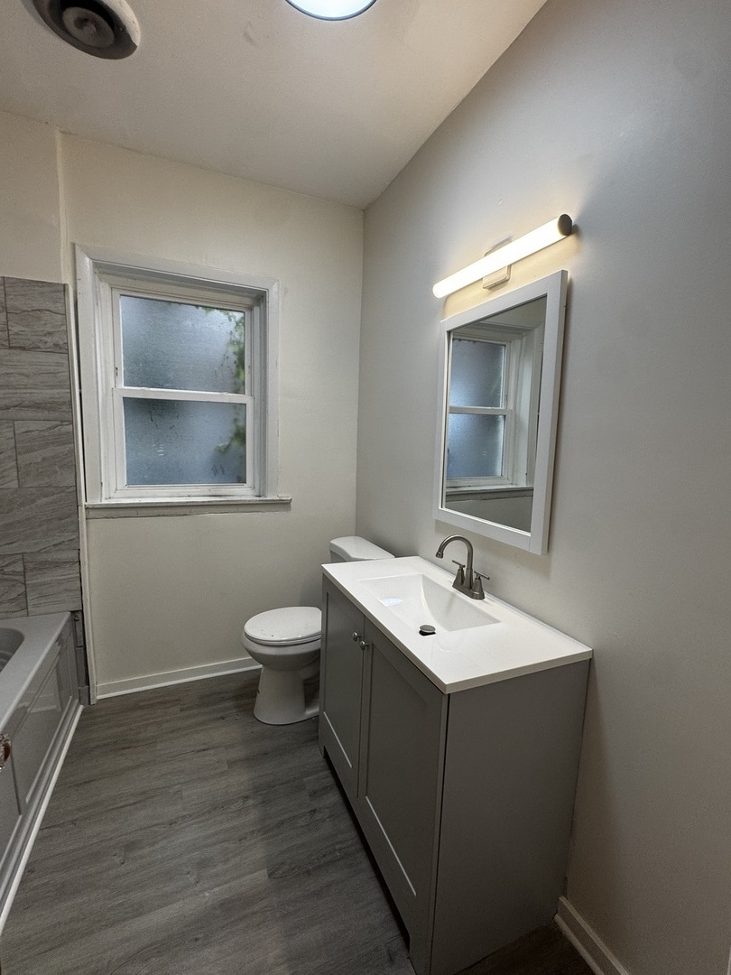 6937 South Merrill Avenue, Unit 1 Chicago, IL 60649 - Photo 6 of 17 a bathroom with a toilet sink and mirror