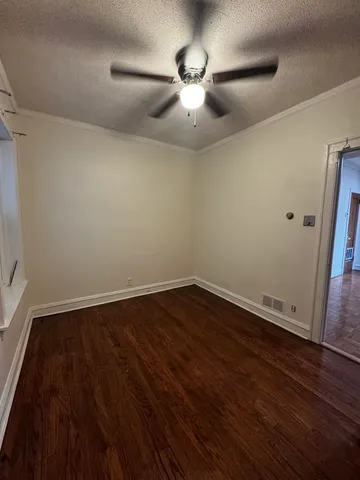 an empty room with wooden floor and fan