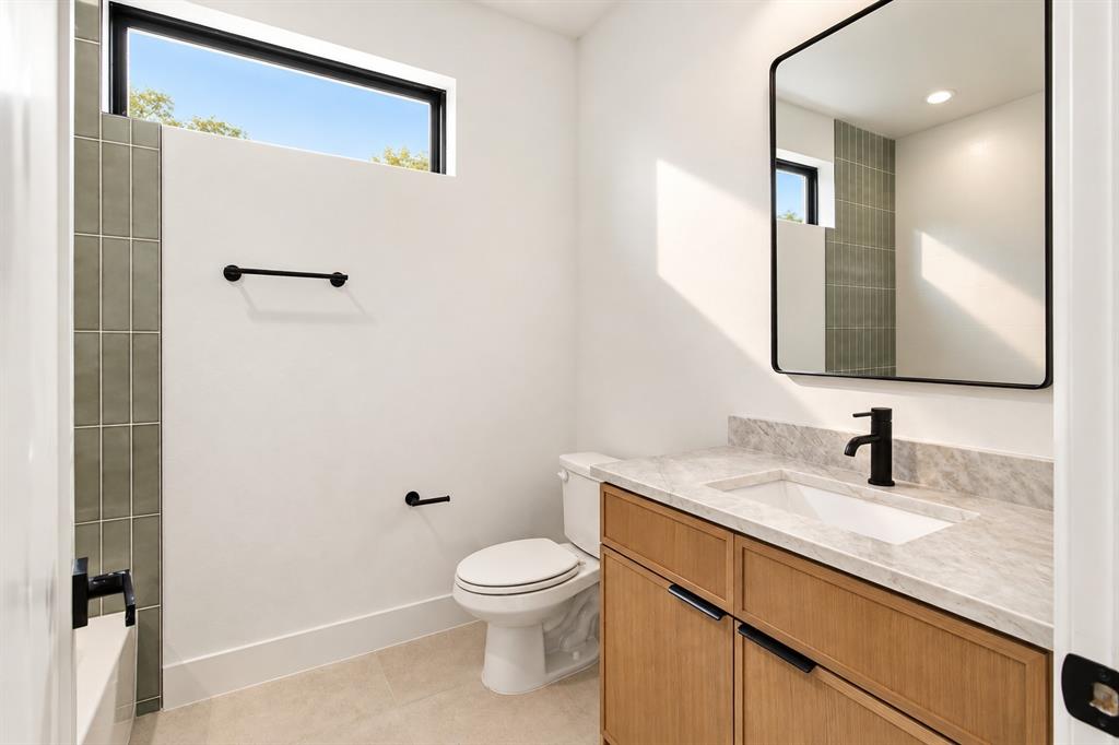 1640 West Wintergreen Road Lancaster, TX 75134 - Photo 33 of 37 Second Modern bathroom featuring a wood-finish vanity with an integrated sink, stone countertop, matte black fixtures, and a rectangular mirror