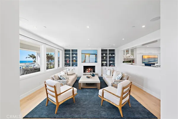 a living room with stainless steel appliances furniture wooden floor and a kitchen view