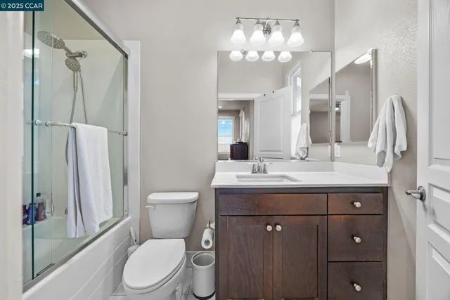 a bathroom with a granite countertop sink toilet a mirror a vanity and shower