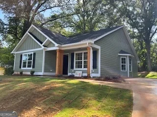 a view of a house with a yard and large tree