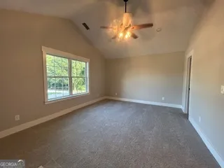 an empty room with a chandelier fan and windows