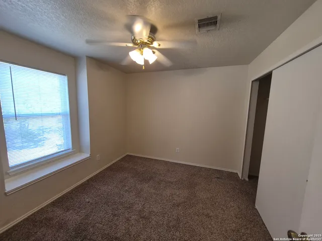 an empty room with windows and chandelier fan