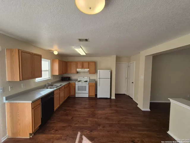 a kitchen with stainless steel appliances granite countertop a stove a sink dishwasher and a refrigerator with wooden floor