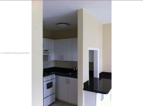 a kitchen with granite countertop white cabinets and black stove top oven