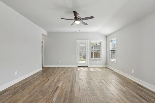 a view of an empty room with wooden floor and a window