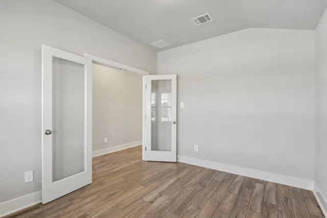 a view of an empty room with wooden floor and closet