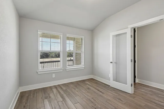 an empty room with wooden floor and windows