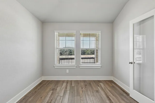 an empty room with wooden floor and windows