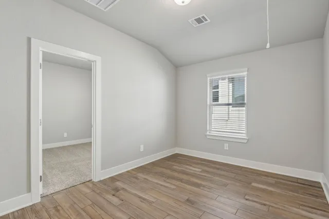 an empty room with wooden floor and windows