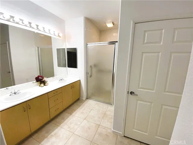 a bathroom with a double vanity sink a large mirror and a shower