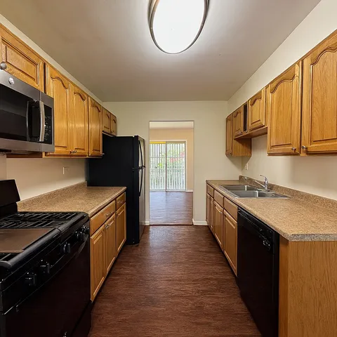 a large kitchen with stainless steel appliances granite countertop a stove top oven a sink dishwasher and a microwave oven with wooden cabinets