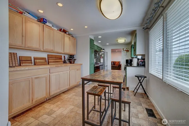 a kitchen with stainless steel appliances granite countertop a table chairs sink and cabinets