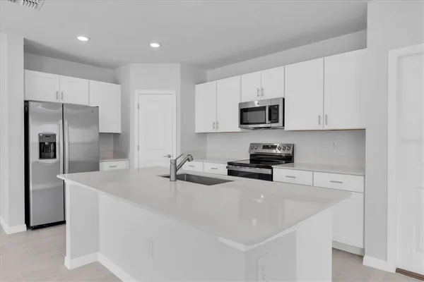 a kitchen with stainless steel appliances granite countertop a sink a stove a refrigerator a microwave and cabinets