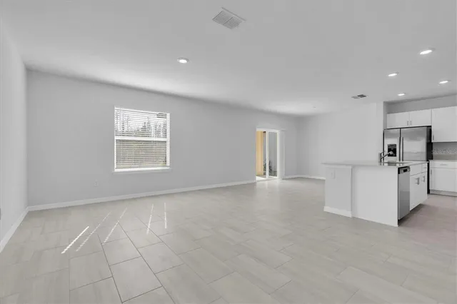a view of empty room with kitchen and window