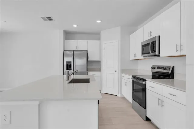a kitchen with white cabinets and stainless steel appliances