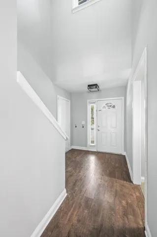 a view of an empty room with wooden floor fireplace and a window