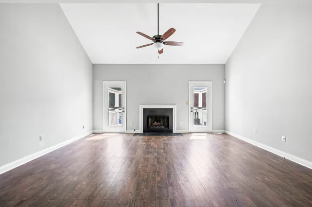 an empty room with wooden floor fan and windows
