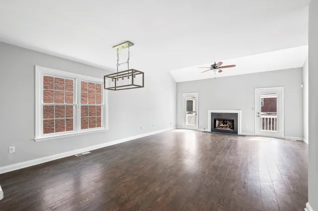 a view of an empty room with wooden floor fireplace and a window