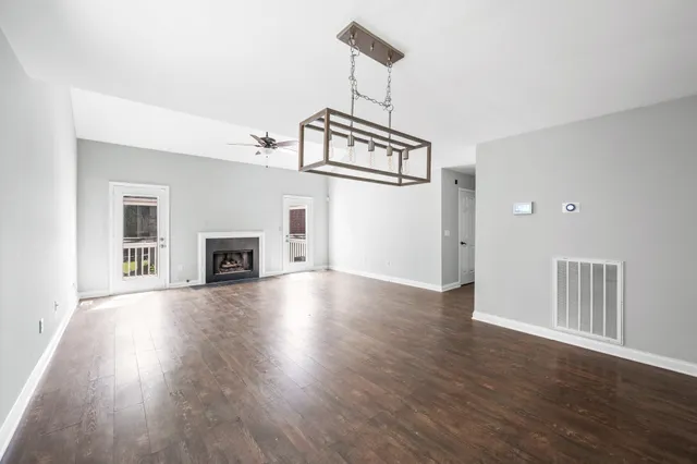 an empty room with wooden floor fireplace and windows