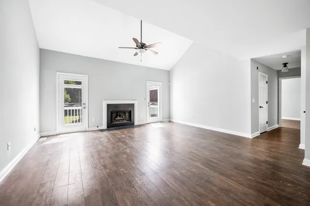 an empty room with wooden floor fireplace and windows