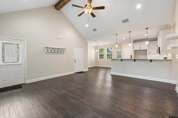 a view of an empty room with wooden floor and a ceiling fan