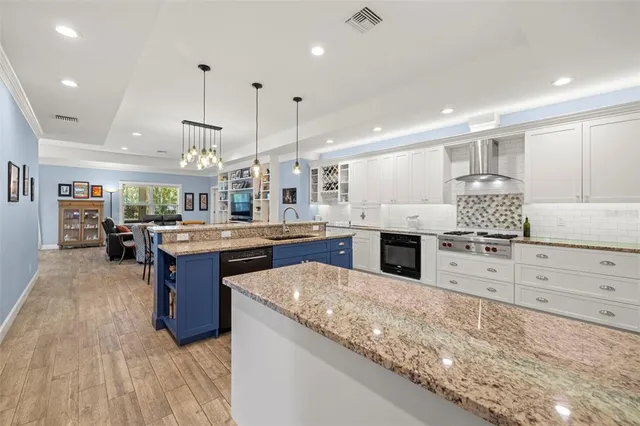 a kitchen with stainless steel appliances kitchen island granite countertop a stove top oven a sink dishwasher and a cabinets with wooden floor