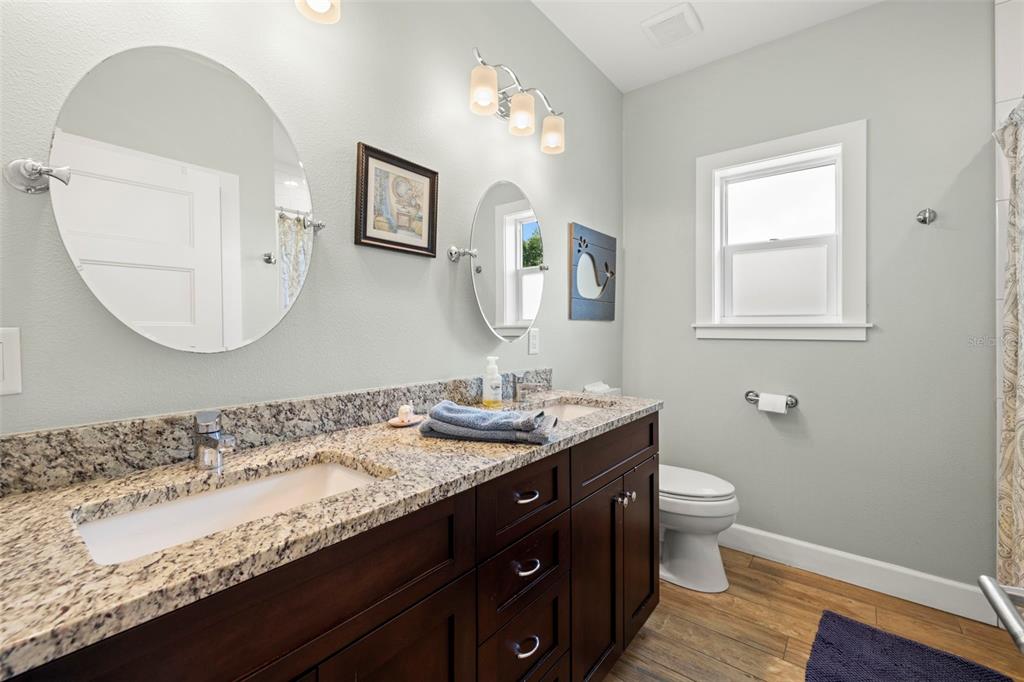2623 57th Street South Gulfport, FL 33707 - Photo 37 of 50 a bathroom with a granite countertop sink a toilet and a mirror