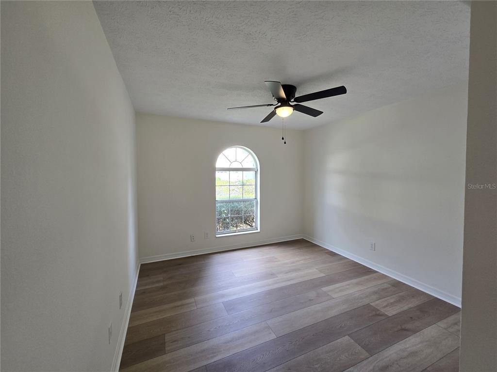 719 Balmoral Court Inverness, FL 34453 - Photo 22 of 29 an empty room with wooden floor chandelier fan and windows